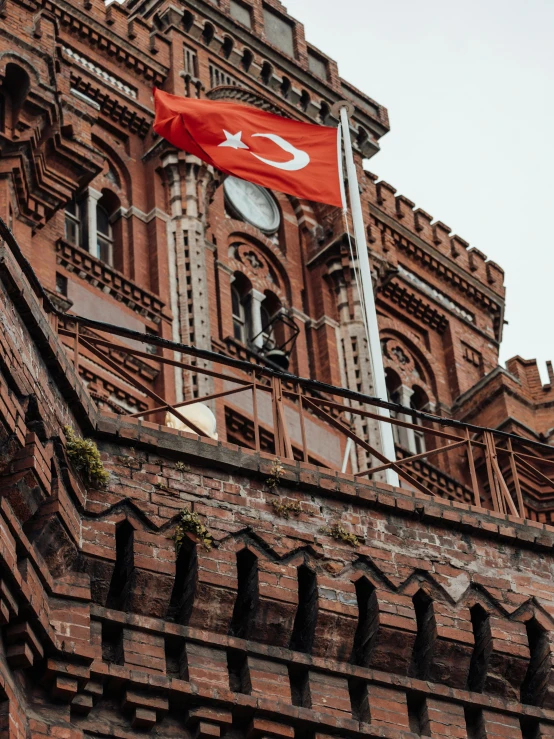 an orange flag flies in front of a large brick building