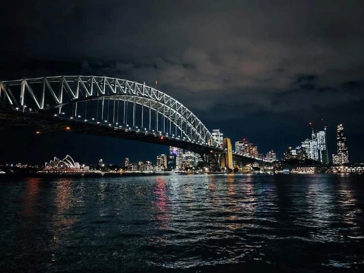 the sydney bridge at night with lights reflected in water