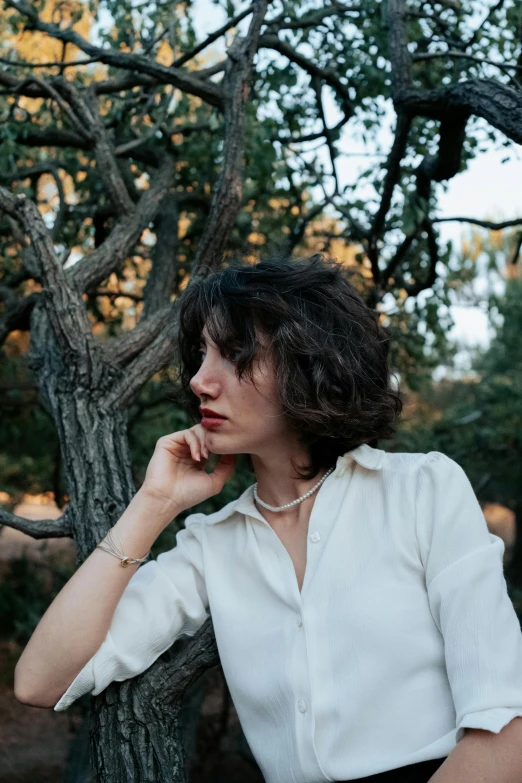 a woman poses in front of a tree