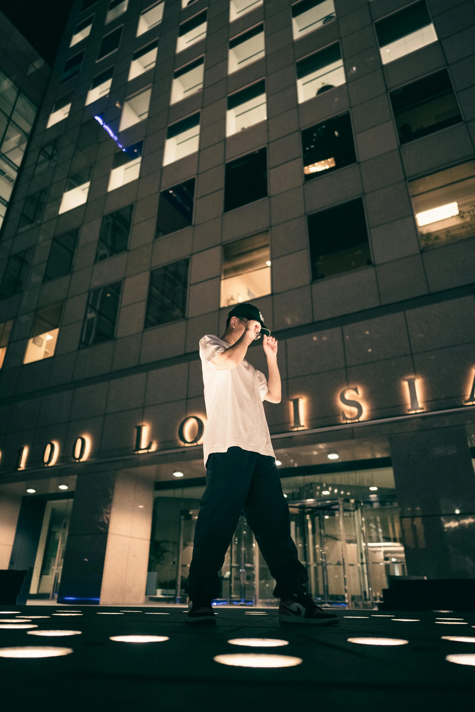 man standing on street in front of a building at night