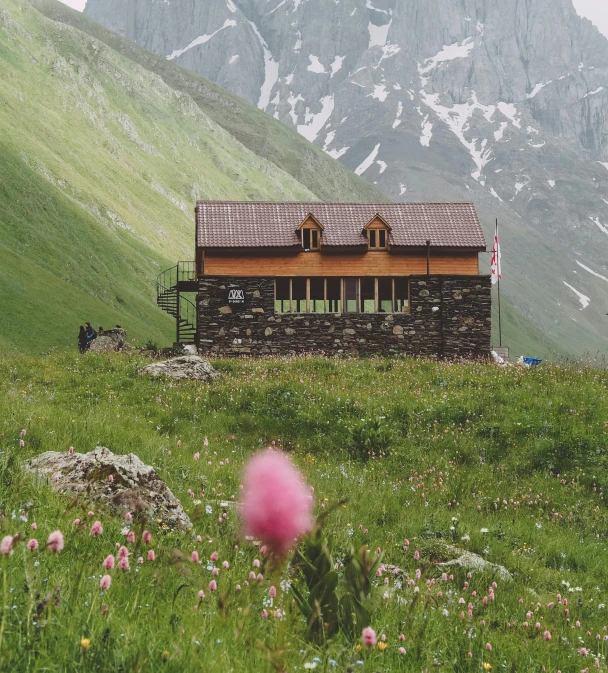 a small structure with a chimney sits on a mountain