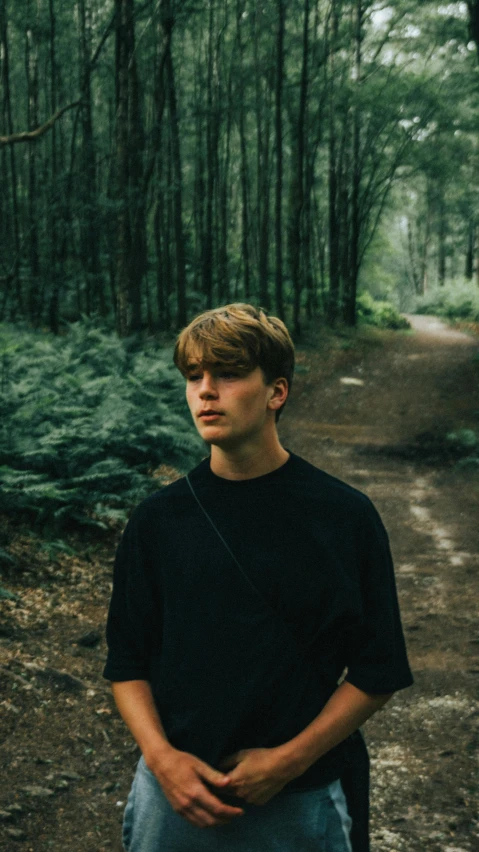 young man standing on path in forest during daytime