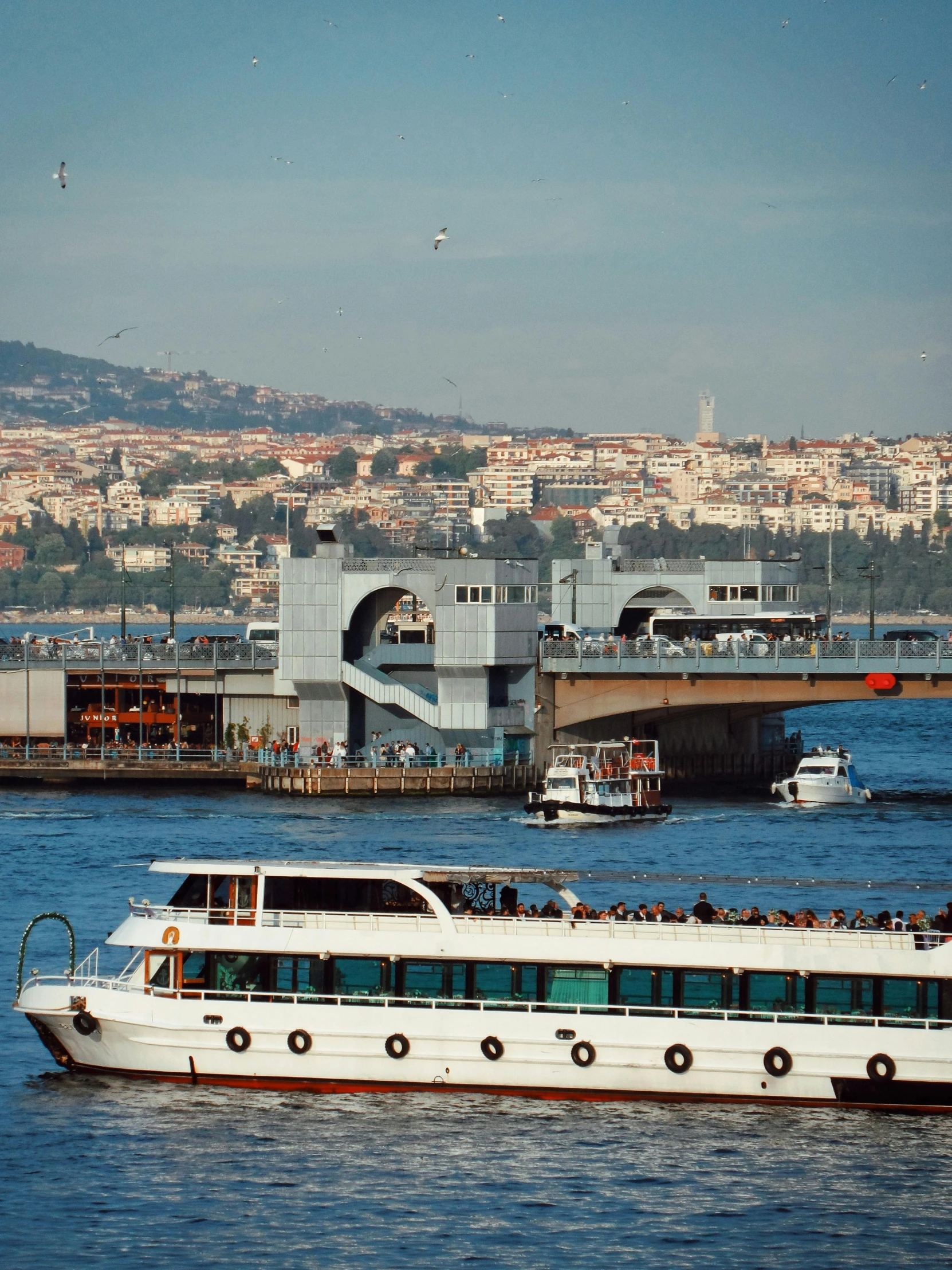 a white ferry boat on a lake near a bridge