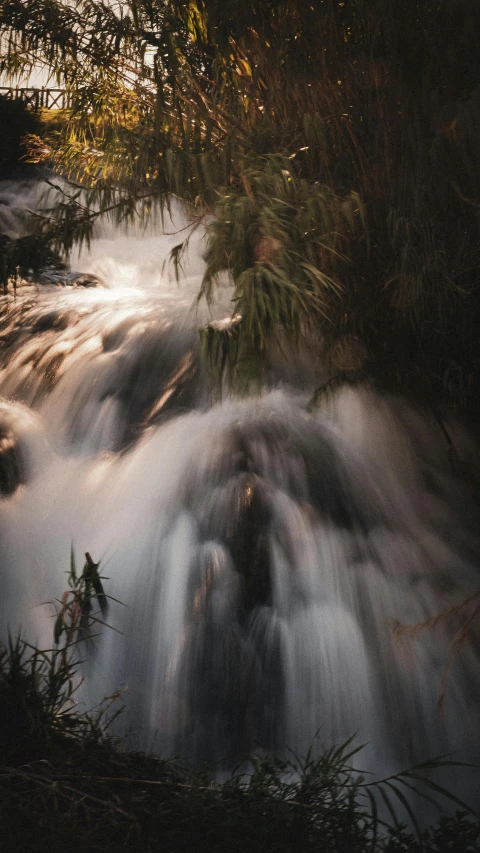 a waterfall in the woods as it is dark