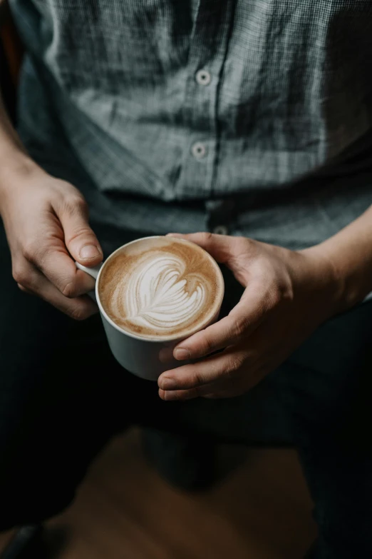 a person holding a cup of coffee in their hand