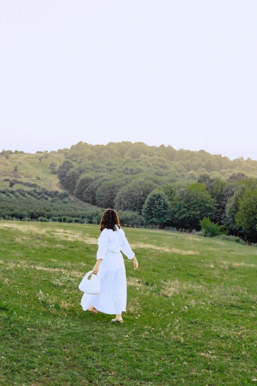 the woman is running down the grass in her dress