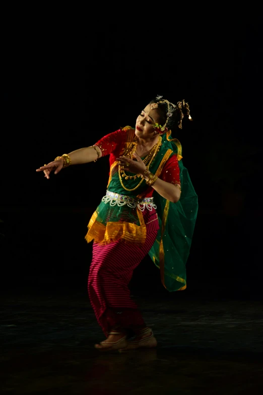 a belly dancer with long green, yellow and red feathers and headpiece