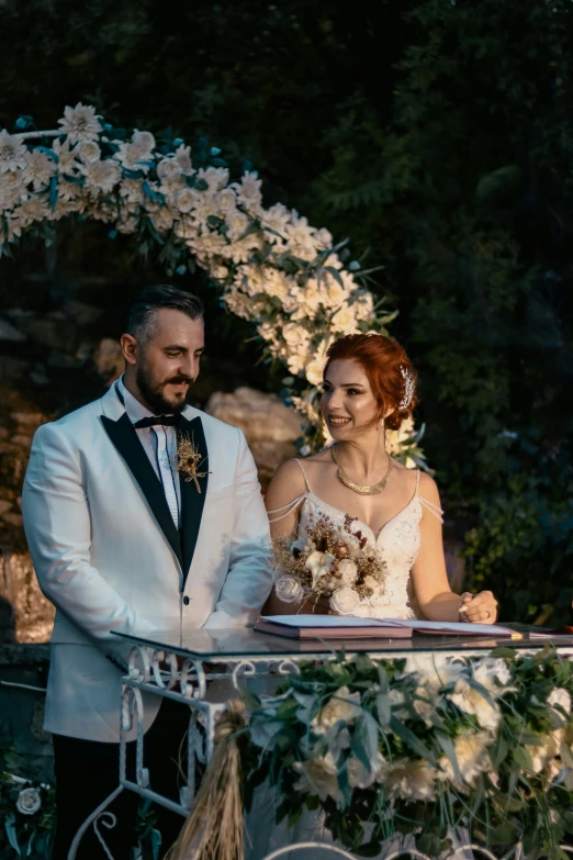 a couple are standing under an arch covered with flowers