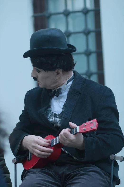 a man with a hat, black jacket and top hat playing a guitar