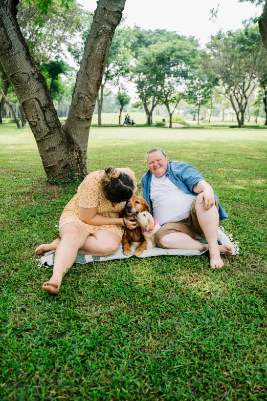 two women hugging while laying on a blanket and dog