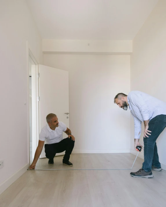 two men stand around the white room, holding the same thing