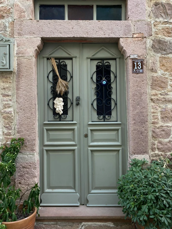 a door with two statues on it in front of some plants