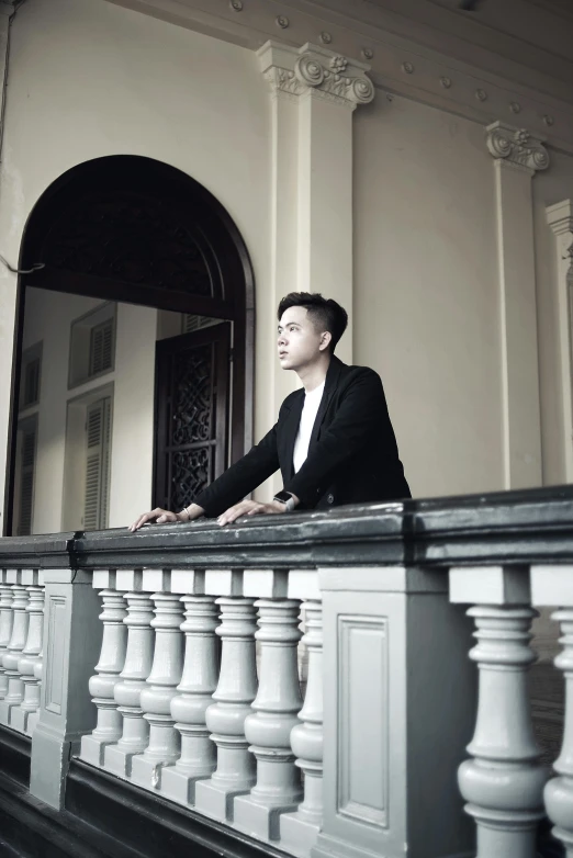 a man sitting on top of a balcony next to a railing