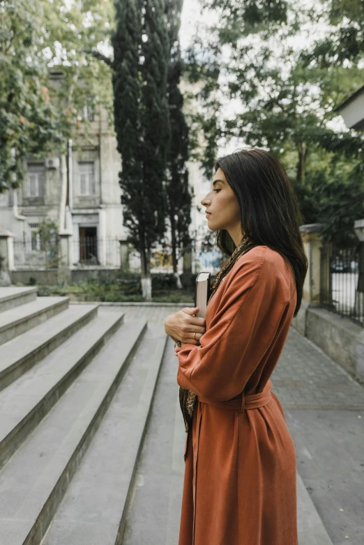 a woman stands in front of some steps and holding a umbrella