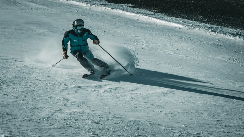 skier in blue going down the snowy mountain side