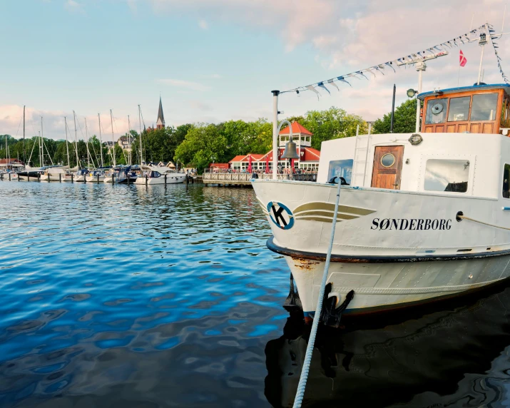 the white boat is tied up to a pole