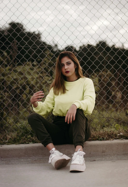 a young woman sitting on the curb with her feet crossed