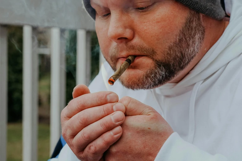 the man is smoking a cigarette and wearing a hat