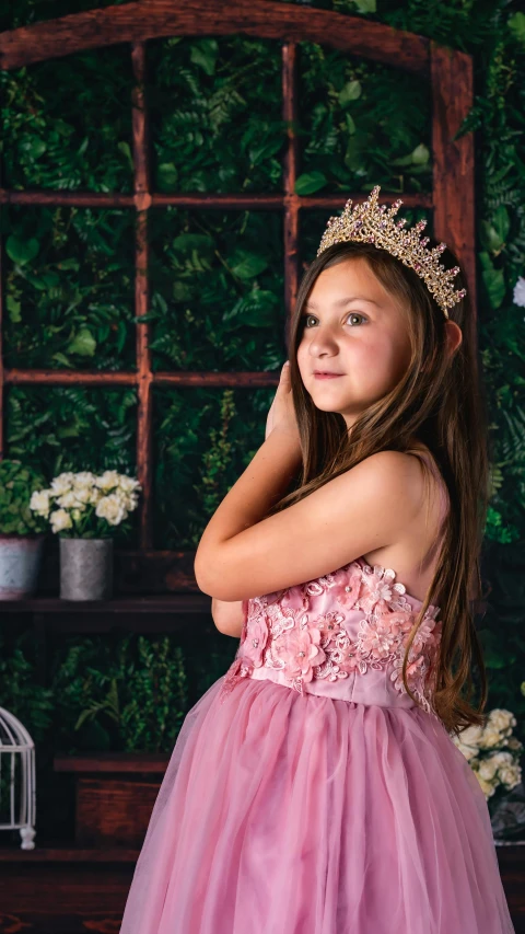  posing wearing pink dress in front of green wall