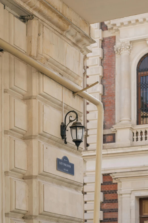 an old fashioned street lamp with a blue sign attached to the side of it