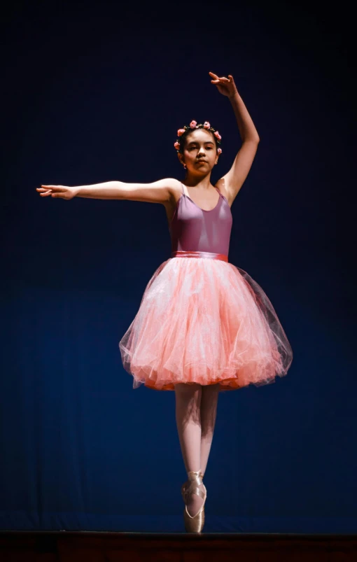 an indian girl performs on stage in a ballet outfit