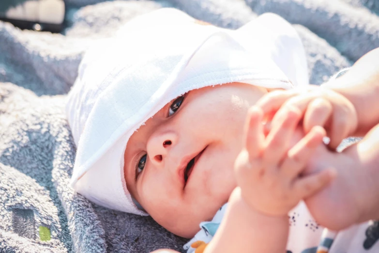 a small child in a white hat laying on the blanket