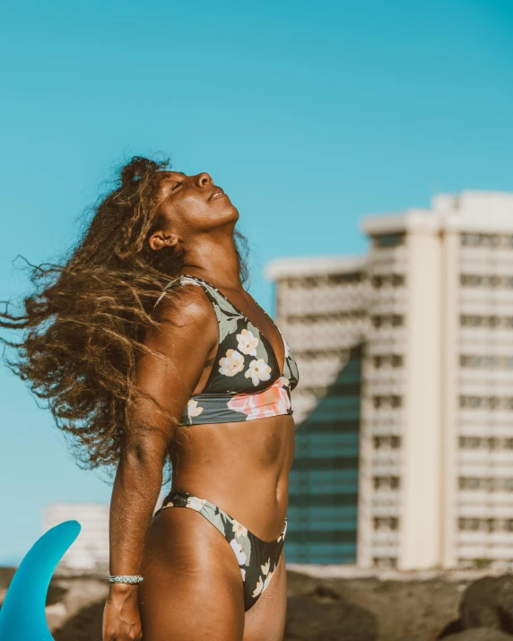 a woman is on the beach with her surfboard