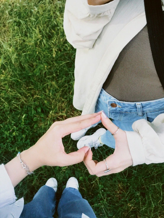 woman sitting on the grass in front of a camera holding an electronic device