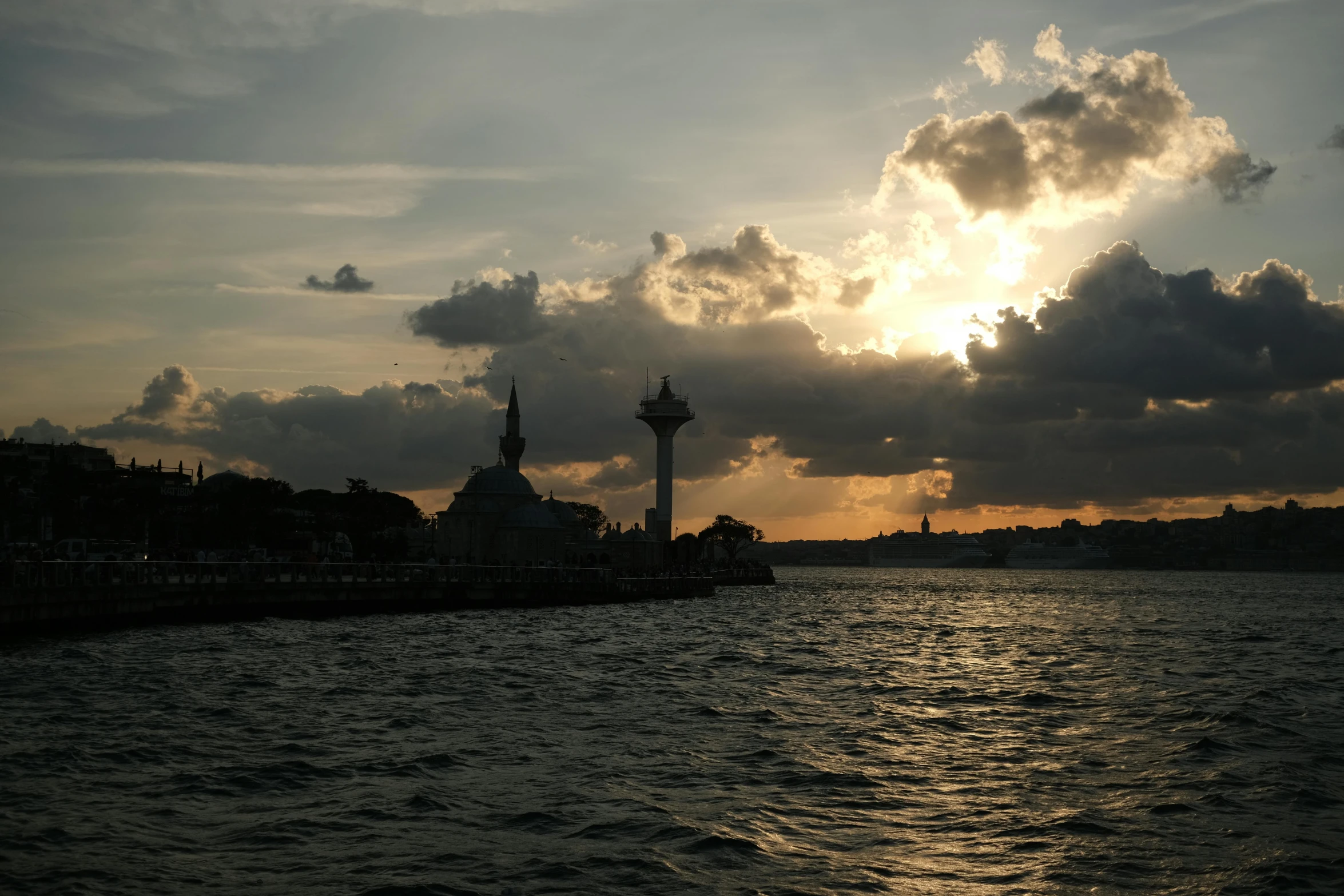 a sun setting over some water with large fluffy clouds