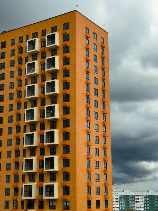 an orange and white building with windows against a cloudy sky