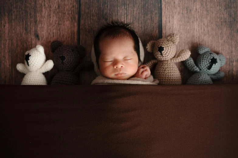 a baby is sleeping next to several knit teddy bears