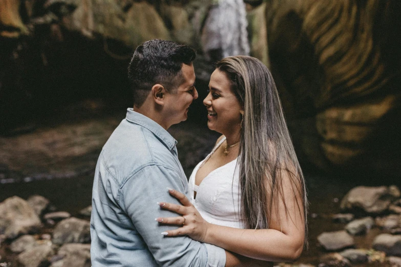 a man and woman emcing by the waterfall