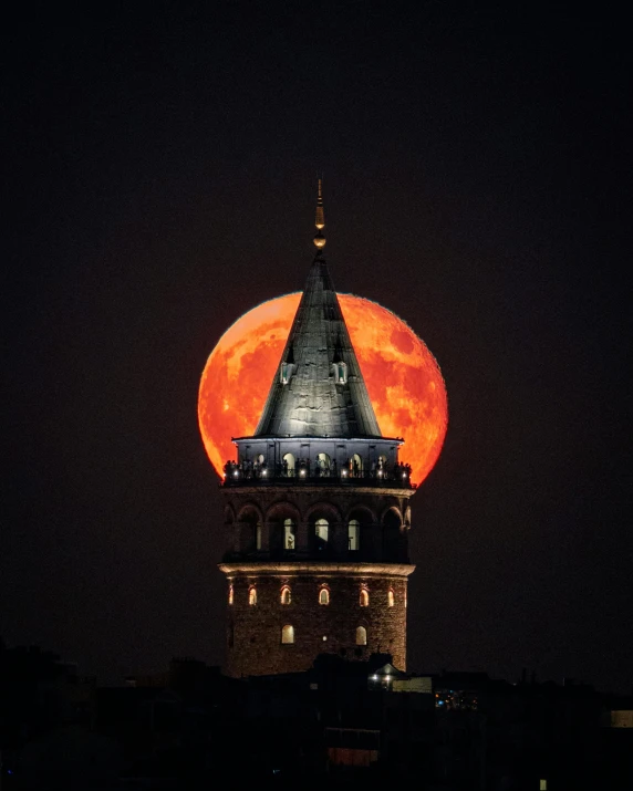 the moon is visible above a building at night