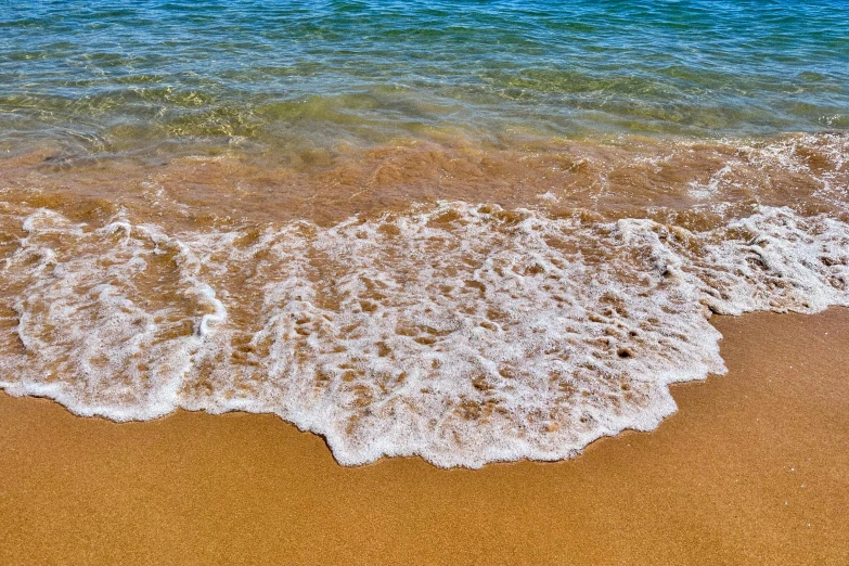 an ocean waves wash up on a sandy beach