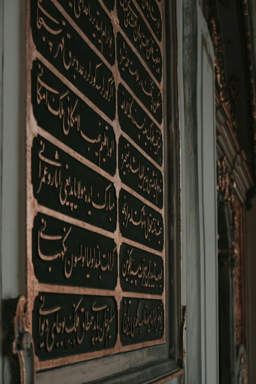 black metal wall plaque with multiple types of writing on it