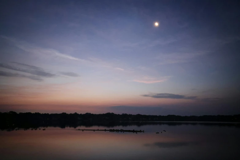 a full moon reflecting in a calm body of water