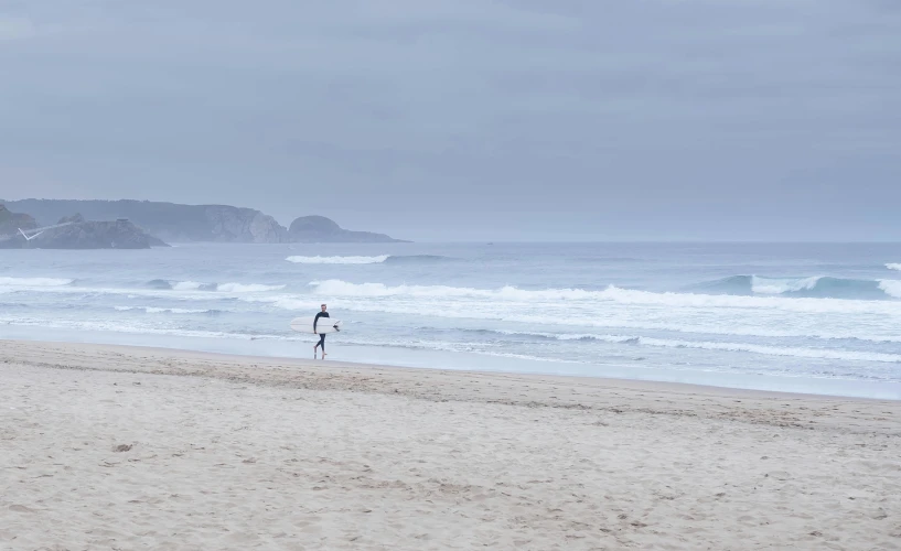 a person walking on the beach in front of an ocean