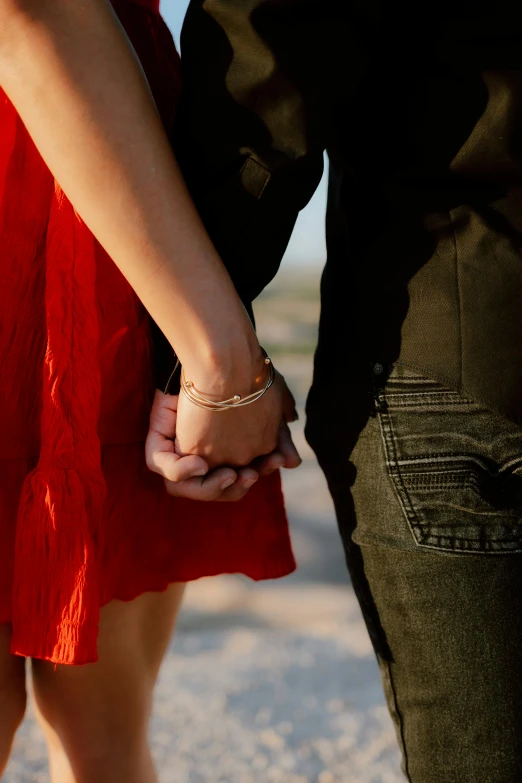 close up of two people holding hands, one woman wearing a red dress and the other holding another hand