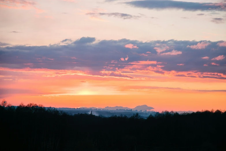 a sunset seen over the mountains from a lake