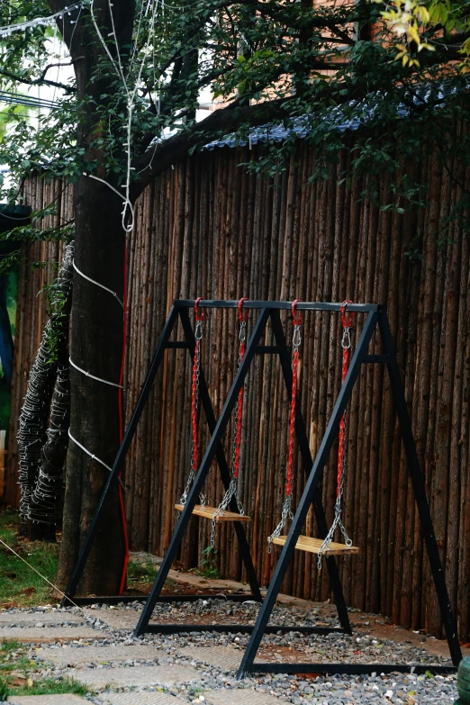 a swing set near a tree on a sidewalk