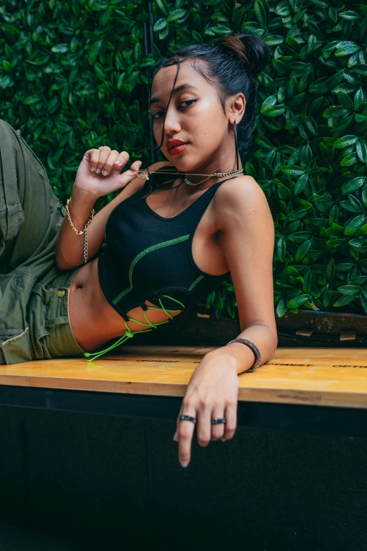 a young woman sitting on a wooden bench wearing a crop top