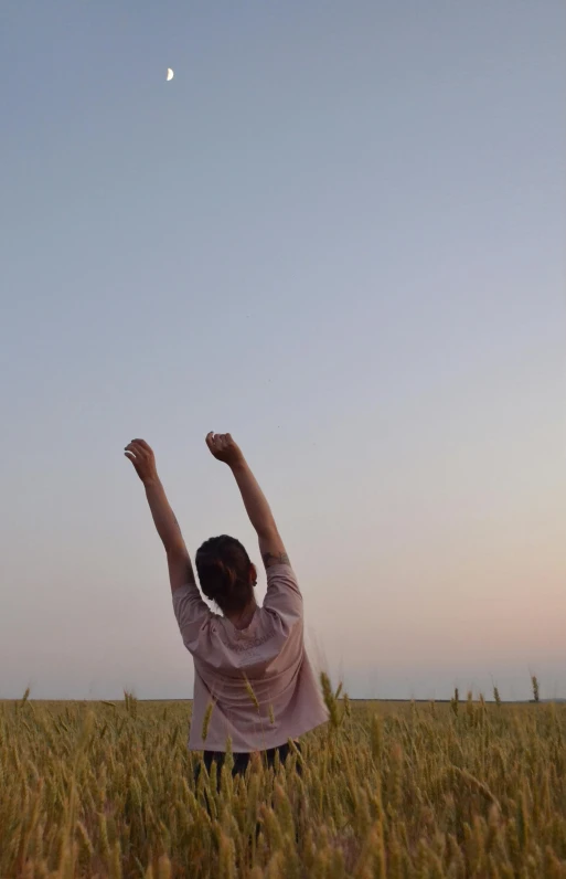 a woman with her hands raised and a kite in the sky