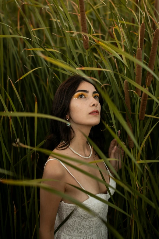 the woman is wearing a necklace standing in a field of grass
