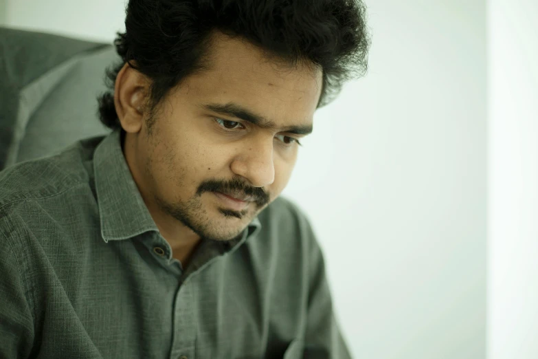 a man sitting and staring ahead wearing a gray shirt