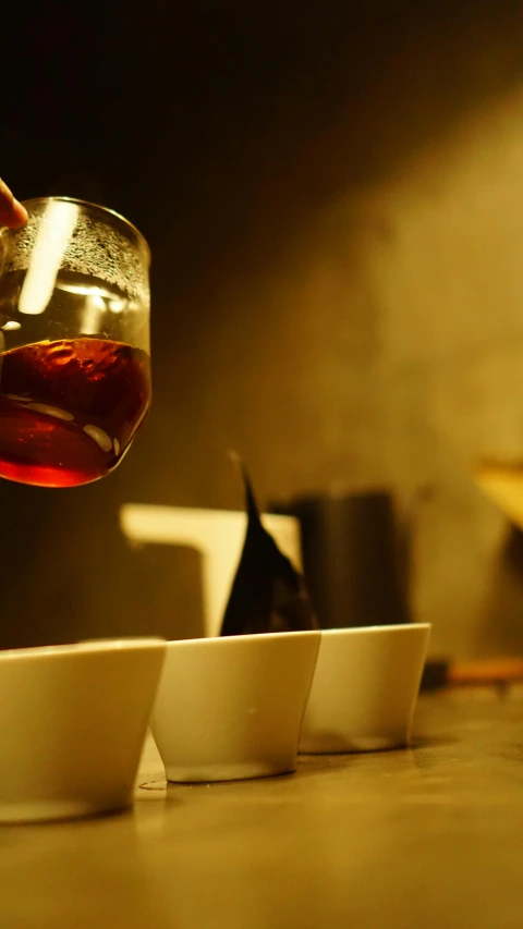 a person holding a glass in front of some bowls