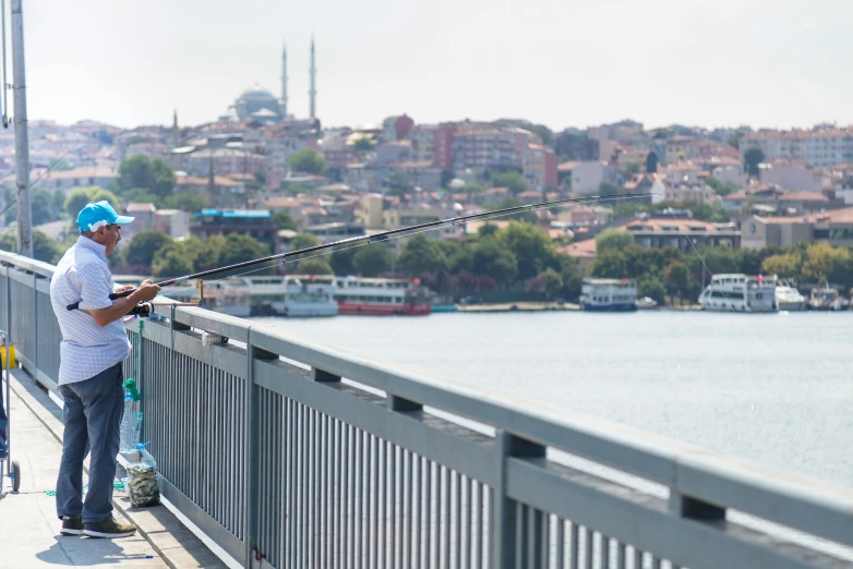 a man is on the edge of the bridge with his fishing rod