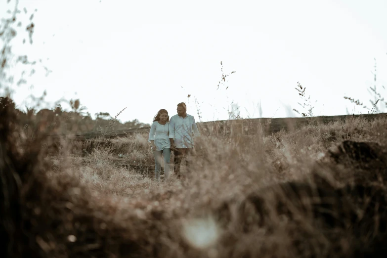 the man and woman walk away from each other through tall grass