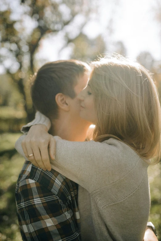 a man and woman hug while they are in the woods