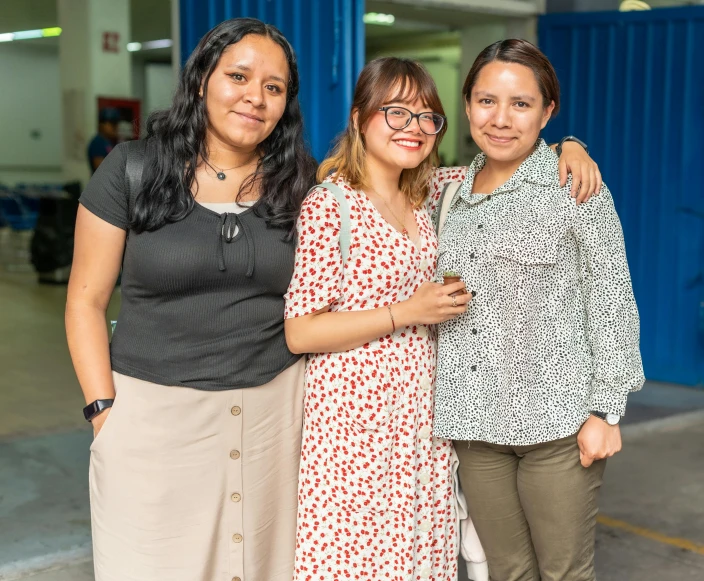 three women standing together, one with her arm around the other