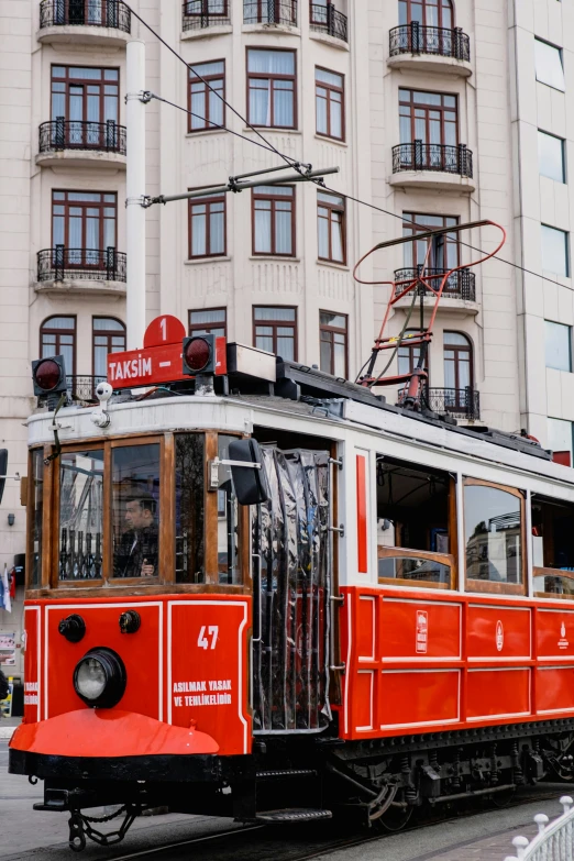 an old, very red trolley train is going down the tracks